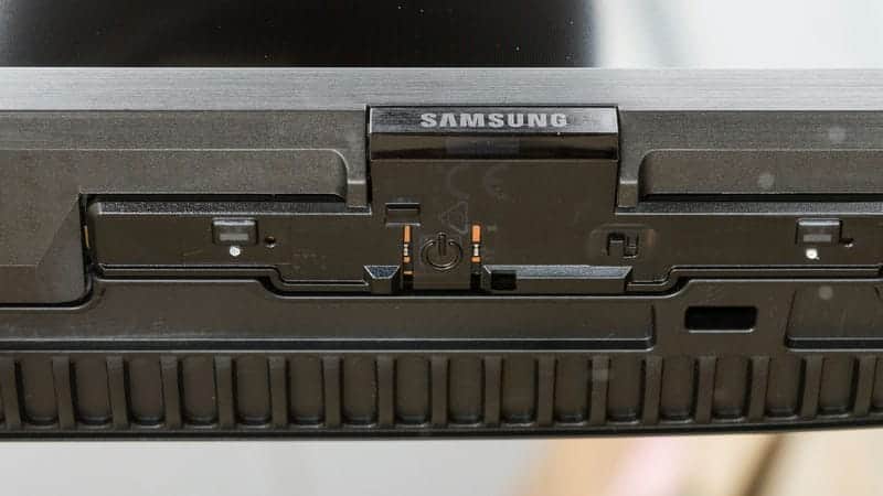 دکمه ی پاور و لوگوی سامسونگ و گیرنده ی مادون قرمز در لبه ی پایینی تلویزیون NEO QLED سامسونگ 85QN85D سایز 85 اینچ سال 2024 - سایت دبی کوچولو